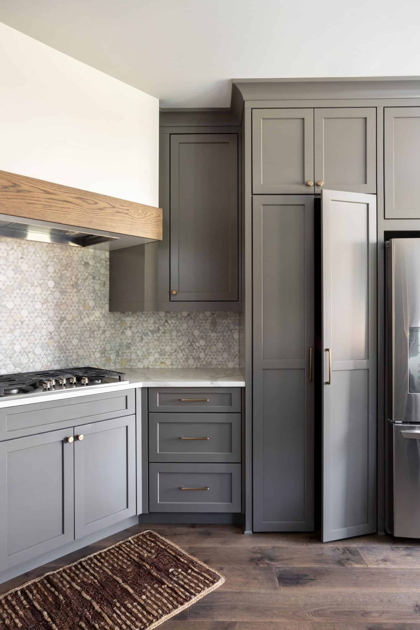 Kitchen with gray cabinetry, natural wood floors, a textured backsplash, and a large central island.